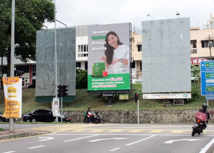 Roadside billboard advertising displayed at a busy city intersection